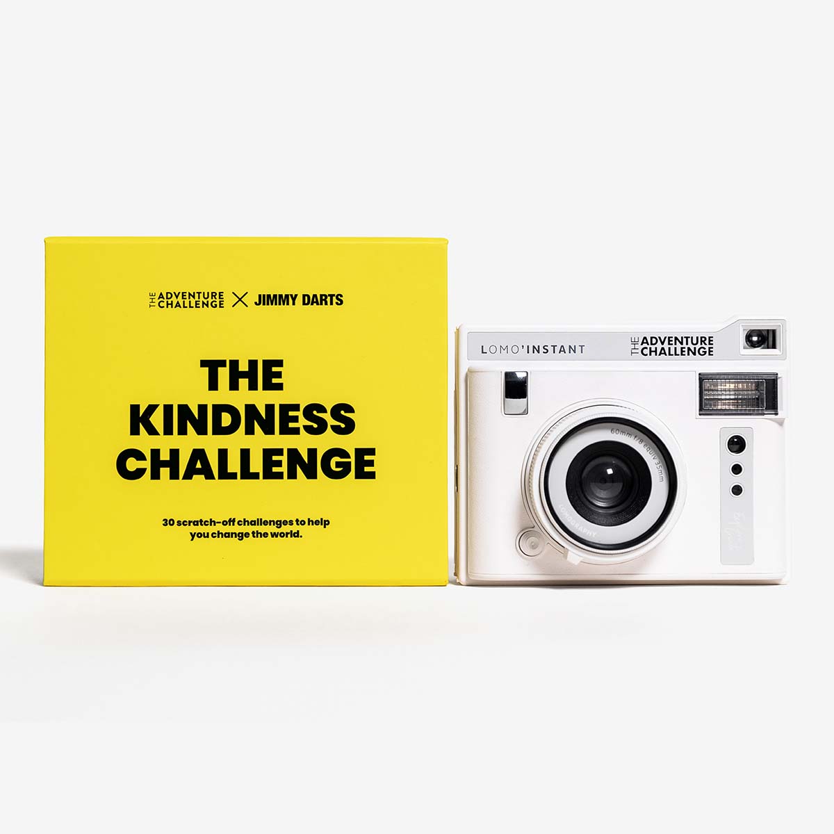 The Kindness Challenge card pack from Jimmy Darts and The Adventure Challenge next to a signature LOMO' Instant Polaroid Camera